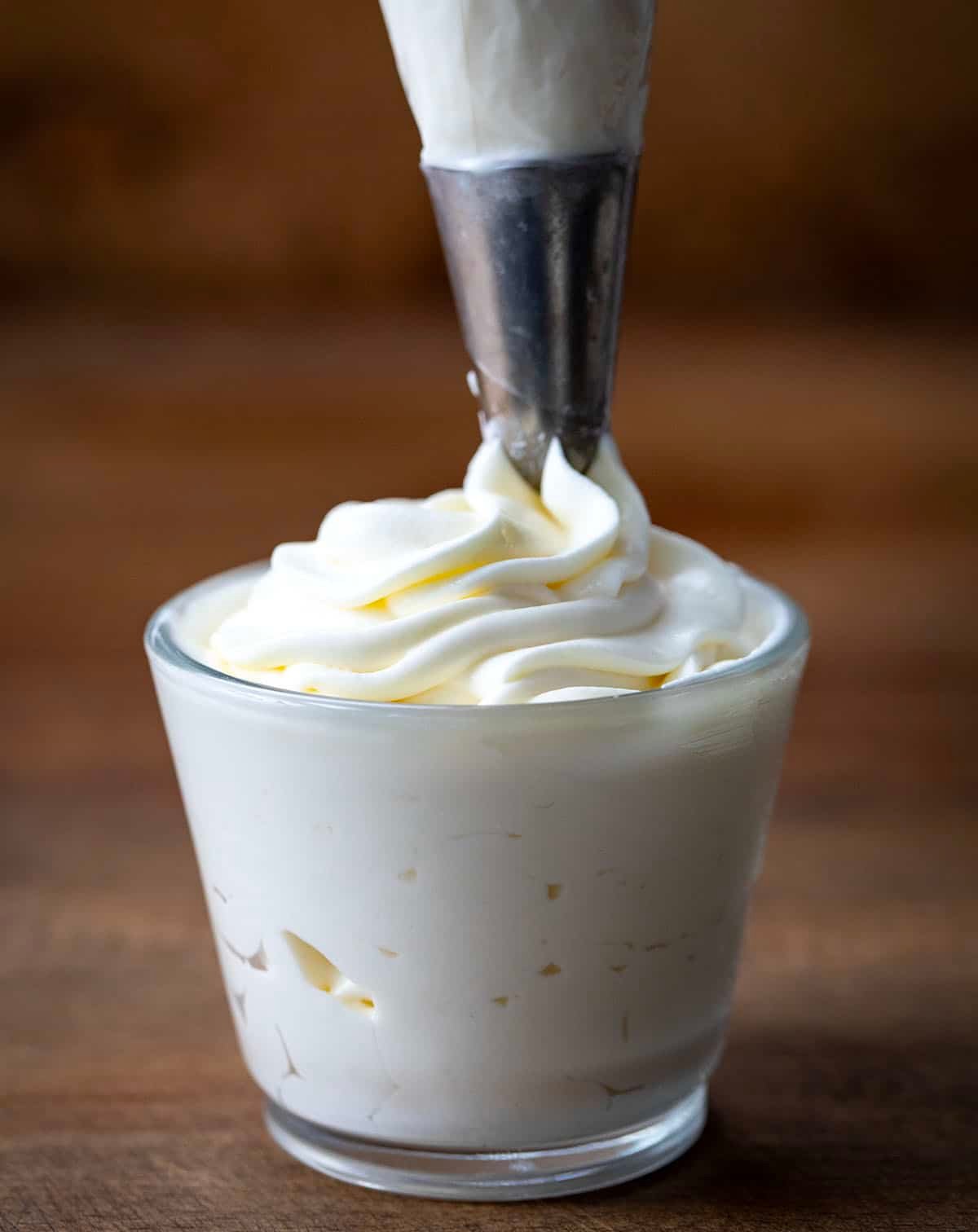 Piping Whipped Cream Cheese Frosting into a shot glass.