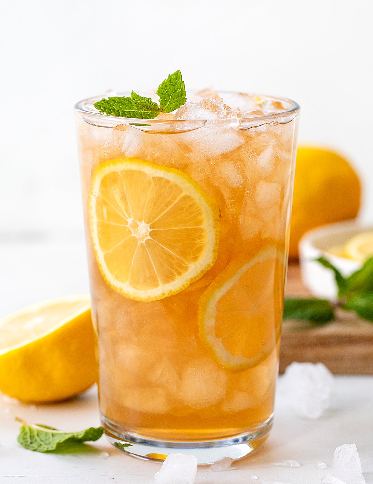 Glass of Arnold Palmer on a white counter with fresh lemon and ice.