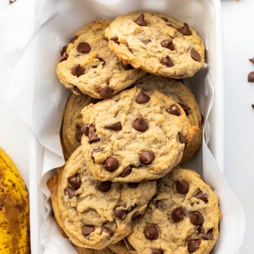 Chewy Banana Chocolate Chip Cookies in a white basket on a white table from overhead.