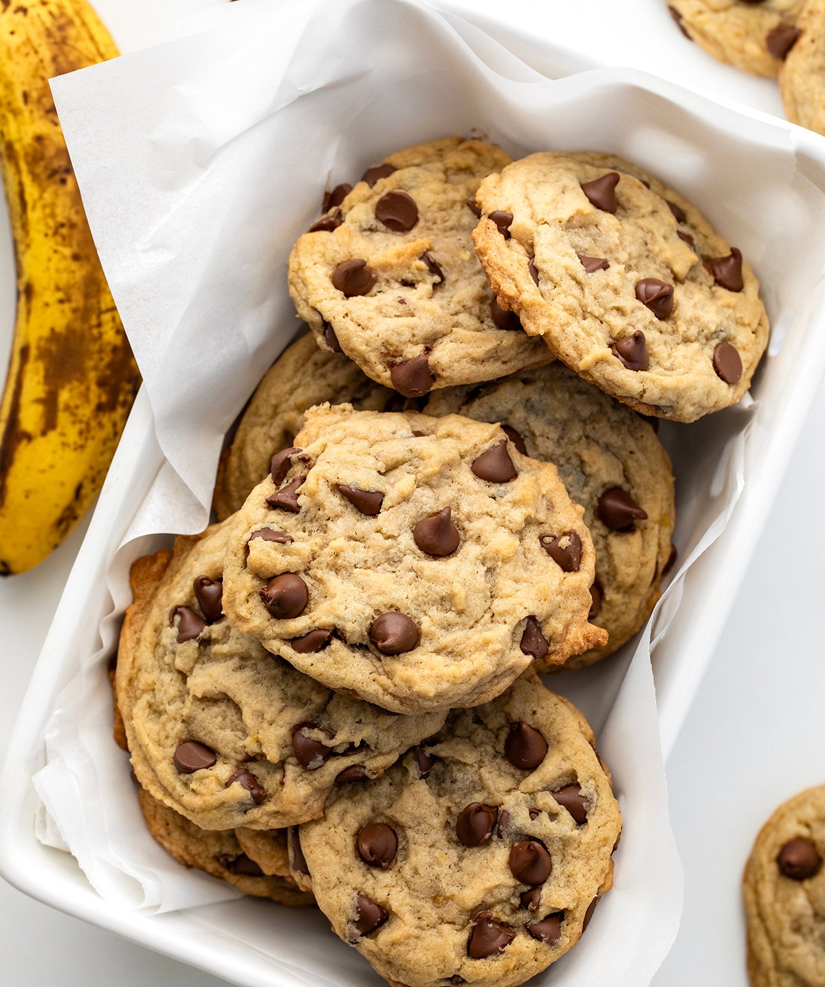 Chewy Banana Chocolate Chip Cookies in a white basket on a white table from overhead.