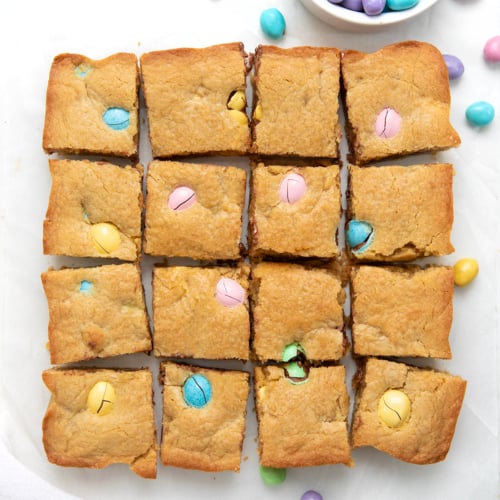 Easter Blondies cut into small squares on a white table from overhead.