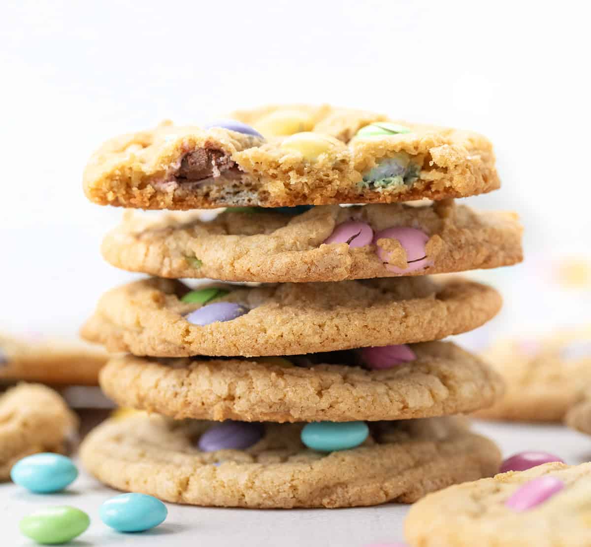 Stack of Easter M&M Cookies with the top cookie broken in half.