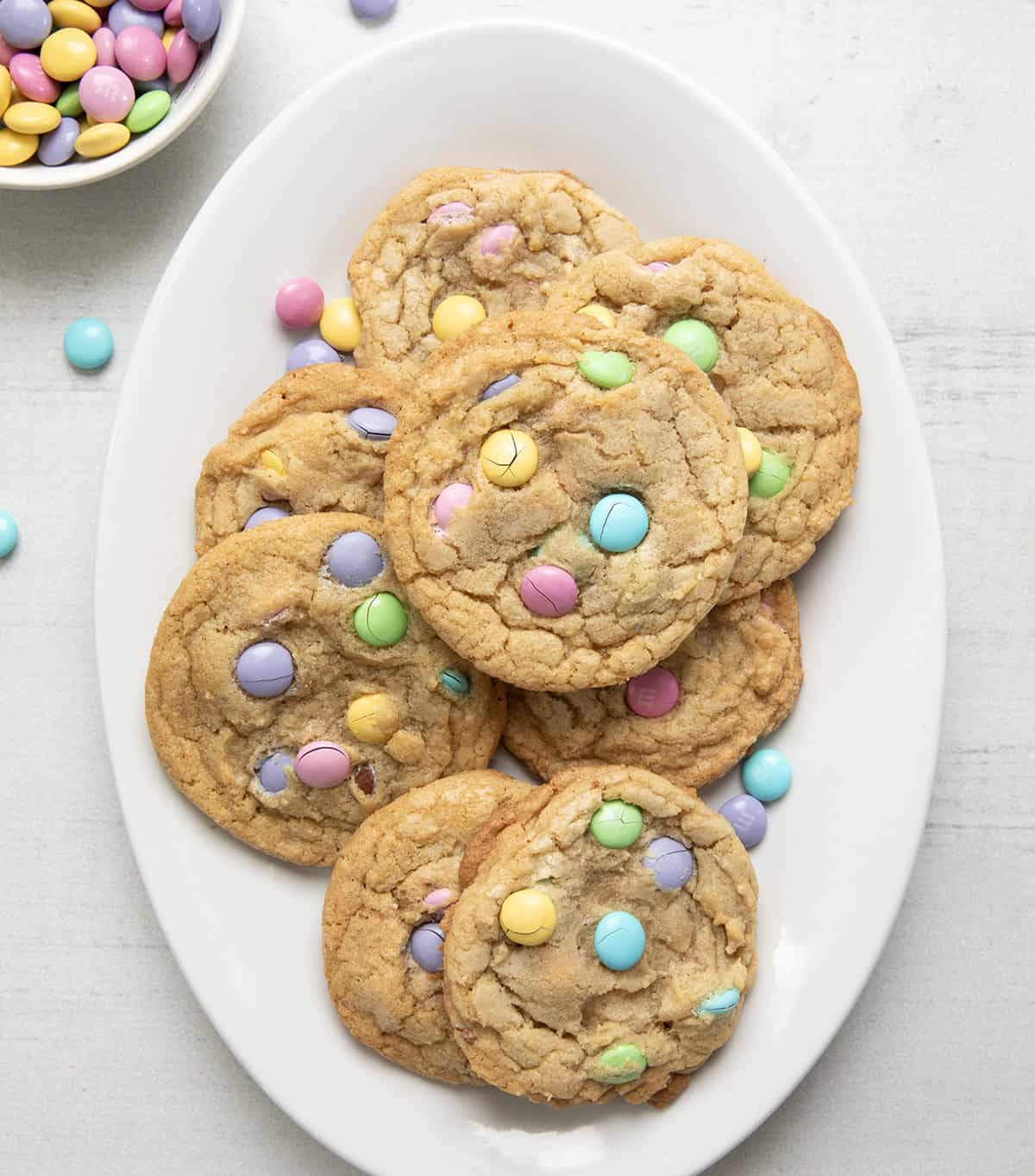 Plate of Easter M&M Cookies on a white wooden table from overhead.