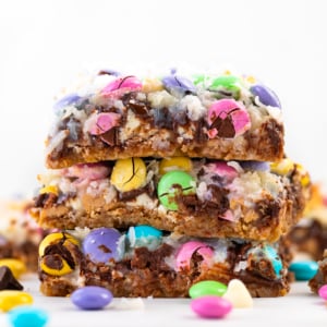 Stack of gooey Easter Magic Cookie Bars on a white table close up.