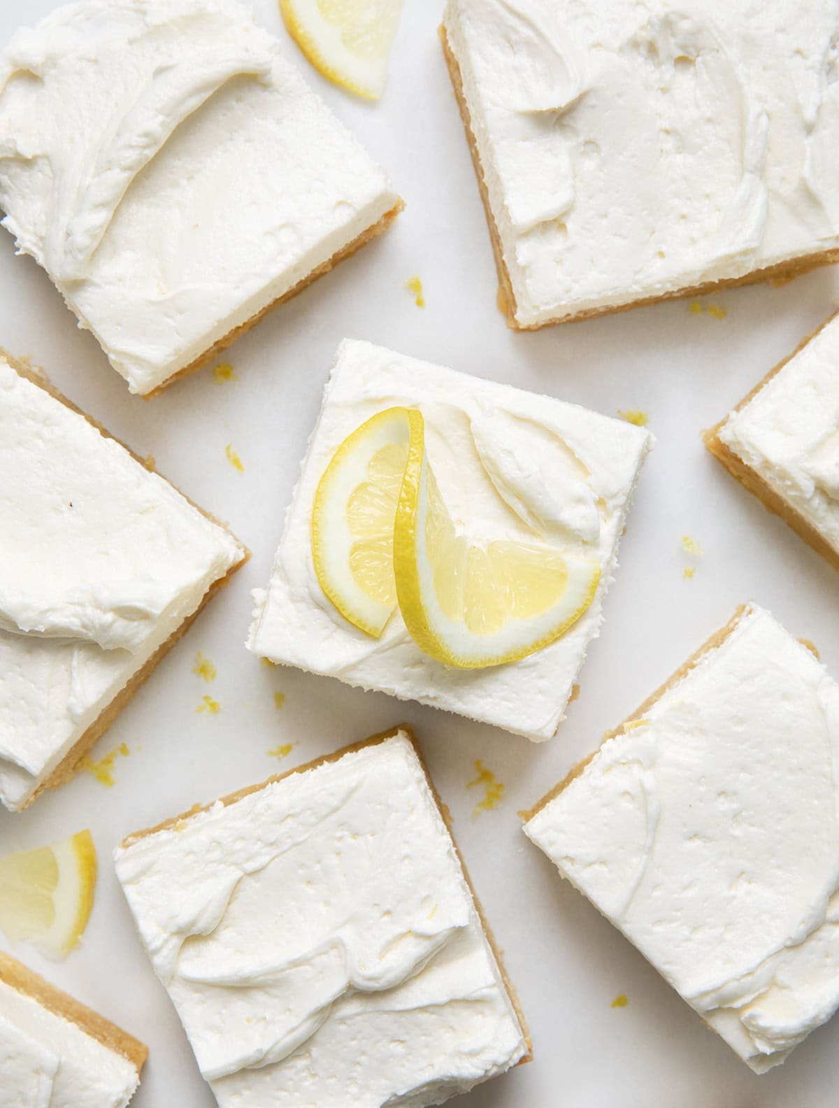 Looking down on a white counter with Frosted Lemon Brownie squares cut up and fresh lemon.