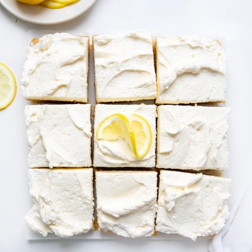 Frosted Lemon Brownies cut into squares on a white table from overhead.