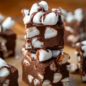 Stack of Hot Cocoa Fudge on a wooden table surrounded by more fudge.