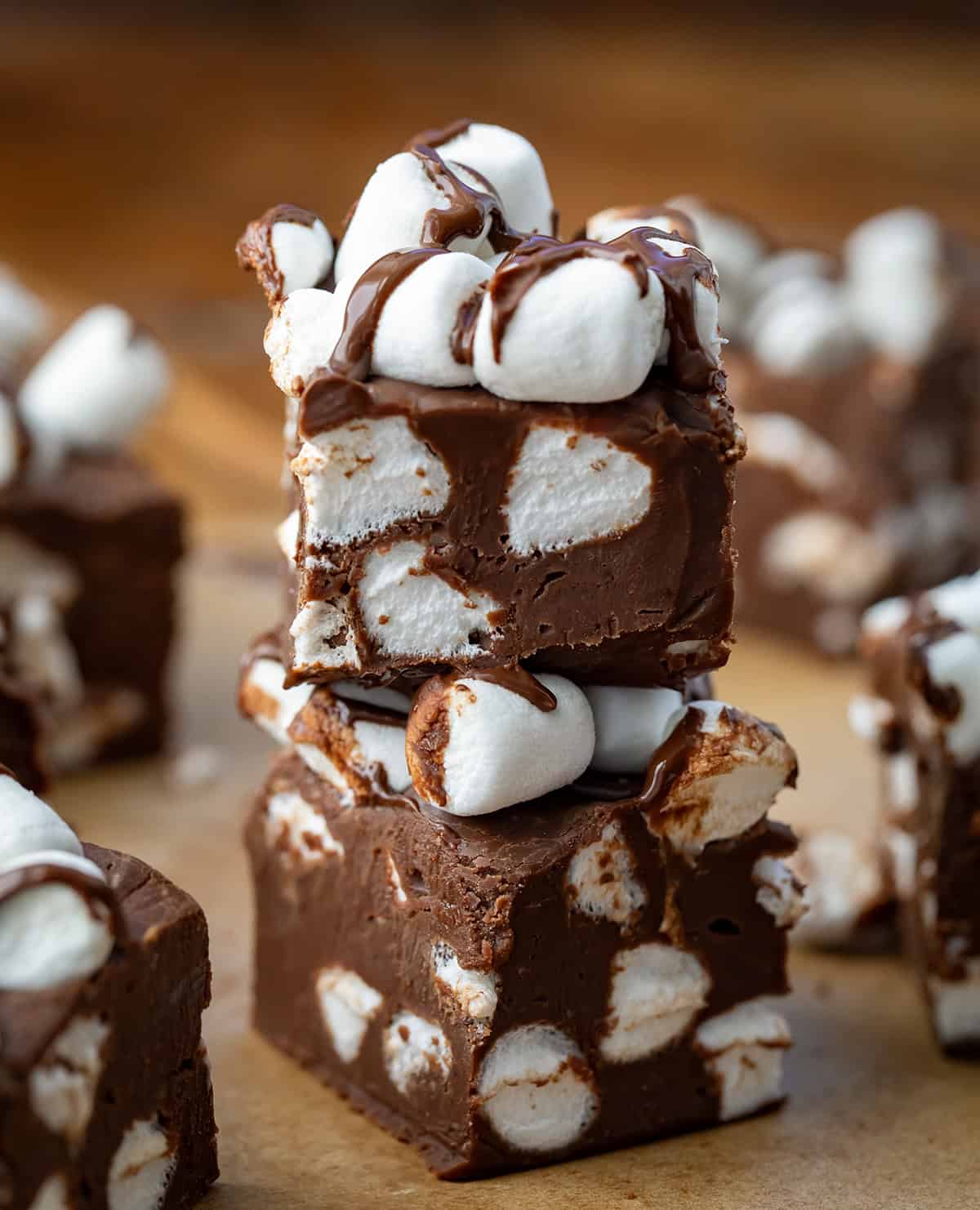 Stack of Hot Cocoa Fudge on a wooden table surrounded by more fudge.