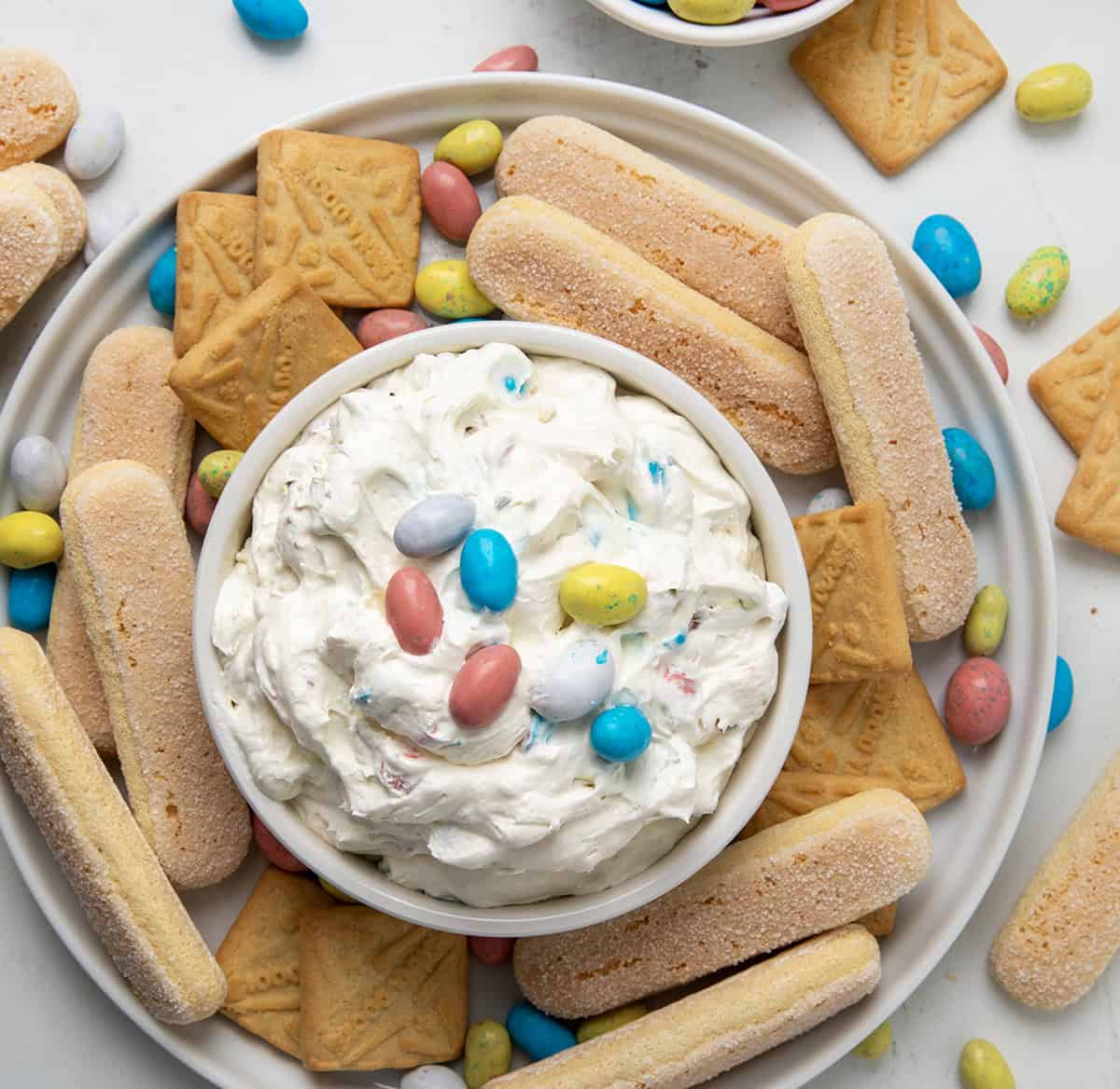 Robin's Egg Dip in a bowl on a plate with cookies and lady fingers around. 