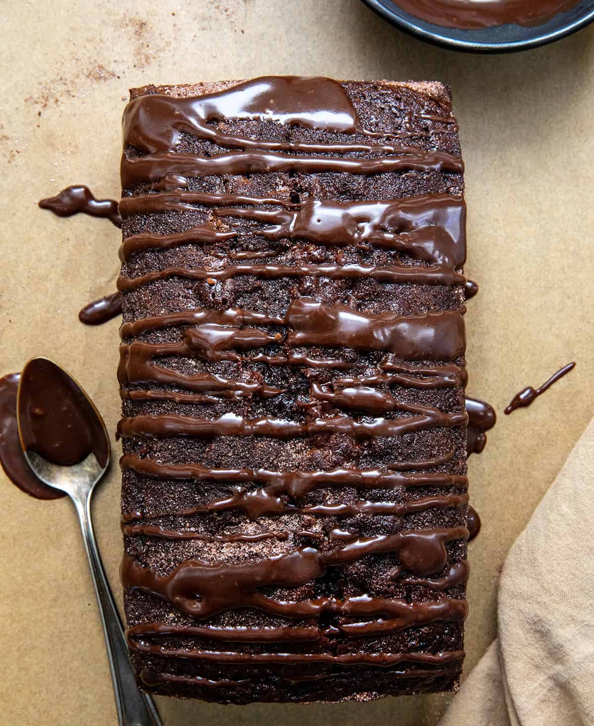 Chocolate drizzled over Chocolate Donut Bread on a wooden table from overhead.