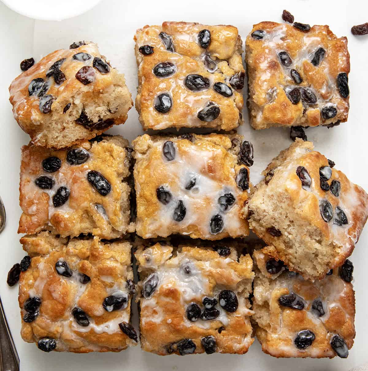 These Cinnamon Raisin Butter Swim Biscuits are a delicious variation of my popular Butter Swim Biscuits, adding the popular flavors of cinnamon and raisins to the mix. Like the original Butter Swim Biscuits, theyโre incredibly soft, fluffy, and filled with rich, buttery goodness, but with an extra layer of texture and sweetness. Cinnamon Raisin Butter Swim Biscuits cut into squares on a white table from overhead.