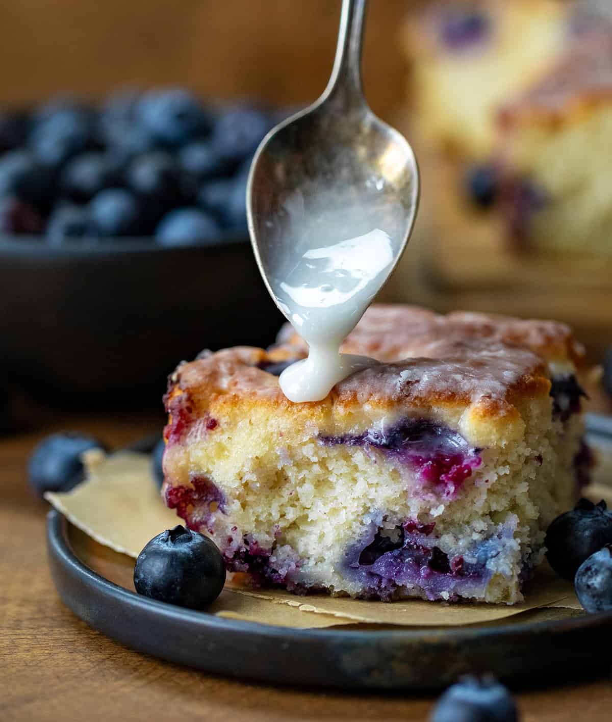 Spoon drizzling glaze over Glazed Blueberry Butter Swim Biscuits.