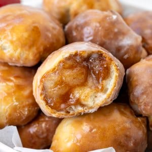 Close up of Apple Fritter Bombs with one apple fritter bomb cut in half showing texture inside.