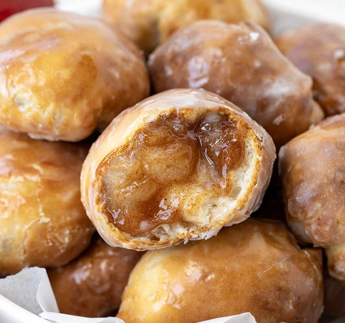 These easy Apple Fritter Bombs are made with biscuit dough, apple pie filling, and a sweet glaze, just like a mini apple fritter! Close up of Apple Fritter Bombs with one apple fritter bomb cut in half showing texture inside.