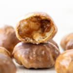Stacked Apple Fritter Bombs with the top apple fritter cut in half showing filling inside.