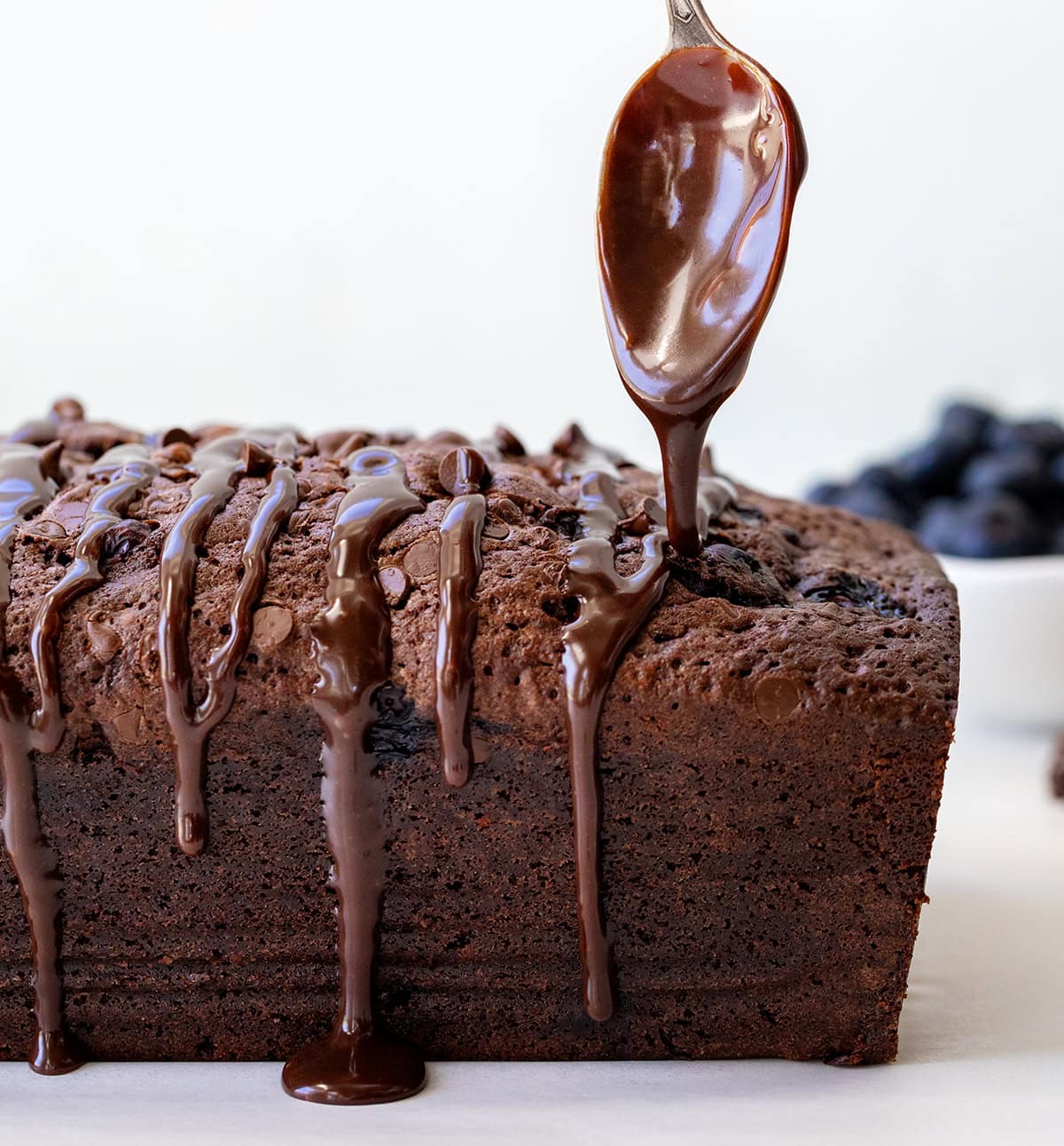 Blueberry Brownie Bread is a rich, fudgy chocolate dessert loaf packed with juicy blueberries and chocolate chips. It’s the perfect mix of a brownie and a quick bread, moist, dense, and full of flavor in every bite! Drizzling ganache over Blueberry Brownie Bread.