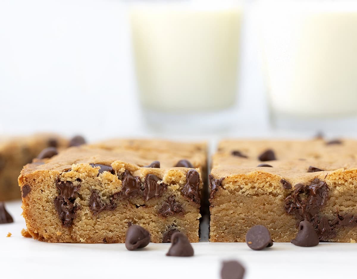 These Browned Butter Chocolate Chip Blondies are rich, chewy, and loaded with melty chocolate chips. If youโre looking for an easy dessert bar that tastes like a bakery treat, youโre in the right place! The browned butter adds a deep, nutty flavor that sets these chocolate chip blondies apart from anything youโve had before. CLose up of Browned Butter Chocolate Chip Blondies on a white table.