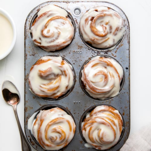 Muffin pan of Cinnamon Roll Cruffins on a white table from overhead.