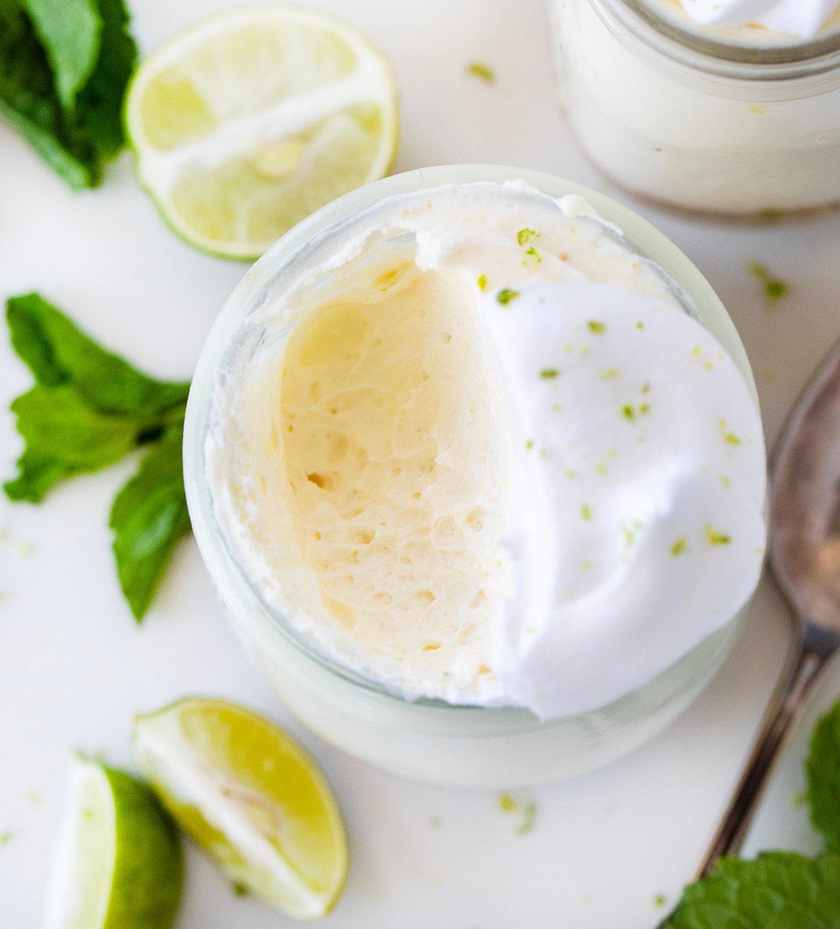 Creamy Key Lime Cheesecake Cups have all the tangy flavor of Key Lime Pie in easy, individual servings, perfect for parties and make-ahead desserts! Jar of Key Lime Cheesecake with a bite removed showing creamy inside texture.