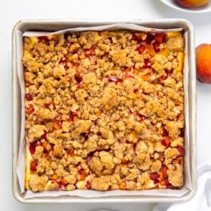 Pan of Peach Cobbler Cheesecake Bars on a white table from overhead.