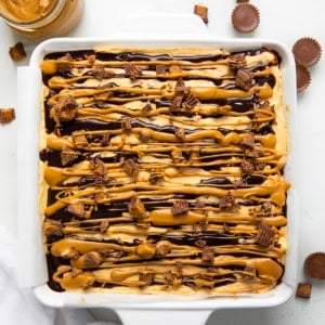 Peanut Butter Cup Cheesecake Bars on a white table with peanut butter cups from overhead.