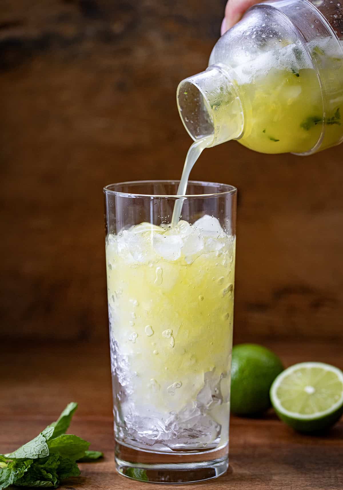 This Pineapple Mojito is a tropical twist on the classic, made with fresh mint, juicy pineapple, lime, light rum, and fizzy club soda for a crisp and refreshing drink. It’s the kind of cocktail you make when you want something that feels a little fancy but takes just minutes to throw together! Pouring Pineapple Mojito into a glass filled with ice.