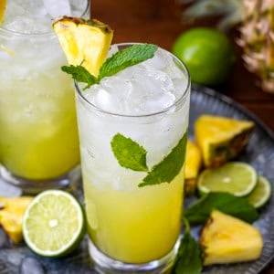 Looking down at Pineapple Mojito's on a tray with fresh lime and pineapple.