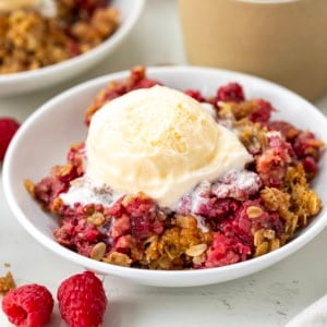 Plate of Raspberry Crisp with a scoop of ice cream on a white table.