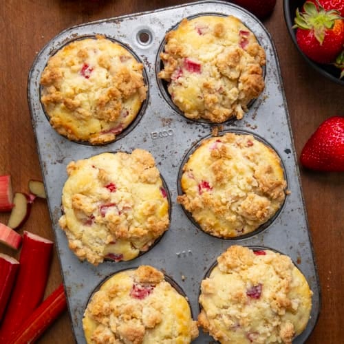 Strawberry Rhubarb Muffins in a pan on a wooden table from overhead.
