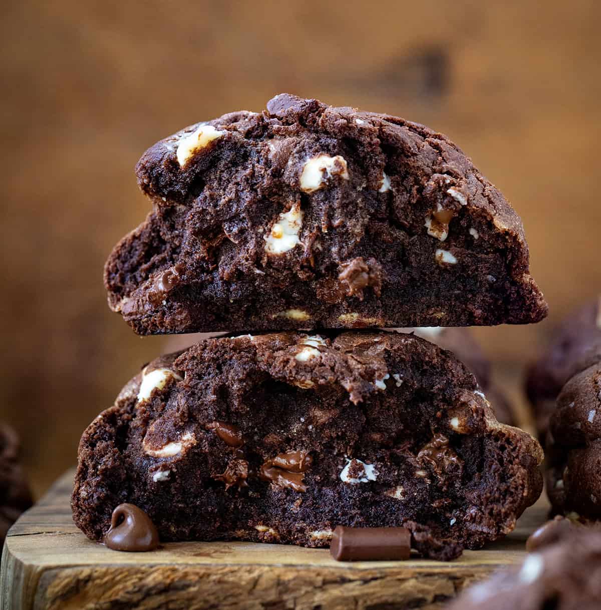 f you love my Ultimate Thick and Chewy Chocolate Chip Cookies, get ready for these Triple Chocolate Chunk Cookies! They are made with three kinds of chocolate (yes, three!), and that ultra-thick, soft-based texture you already know and love! Triple Chocolate Chunk Cookies broken in half and stacked on a wooden cutting board close up.