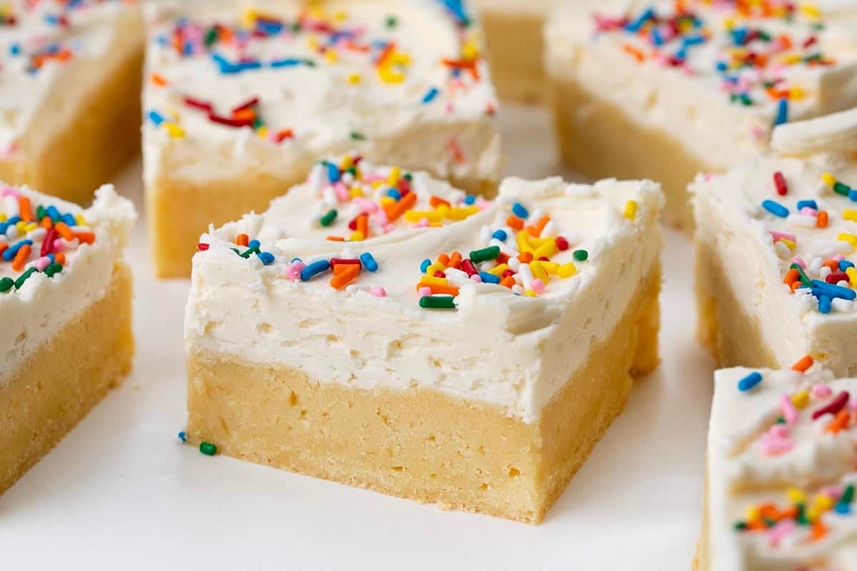 Close up of a Birthday Sugar Cookie Bar on a white table surrounded by other bars.