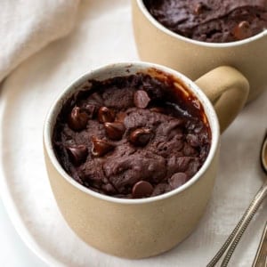 Brownie In A Mug on a white platter on a white table with spoons.