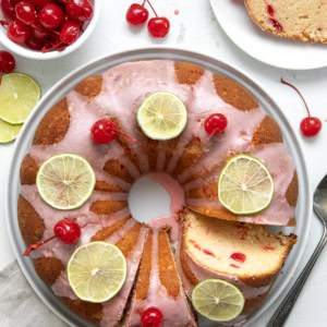 Cherry Limeade Pound Cake on a white cake plate with some pieces cut and one on a plate from overhead.