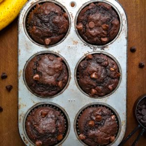 Double Chocolate Banana Muffins in a muffin pan on a wooden table from overhead.