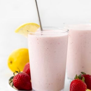 Glasses of Frosted Strawberry Lemonade on a white platter with strawberries and lemons.