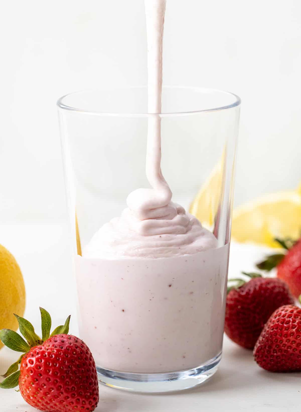I'm all about beating the heat with this super simple, two-ingredient Frosted Strawberry Lemonade, the ultimate refreshing drink for hot summer days! This tangy 2-ingredient treat comes together in seconds and is perfect for kids and adults alike! Pouring Frosted Strawberry Lemonade into a glass.