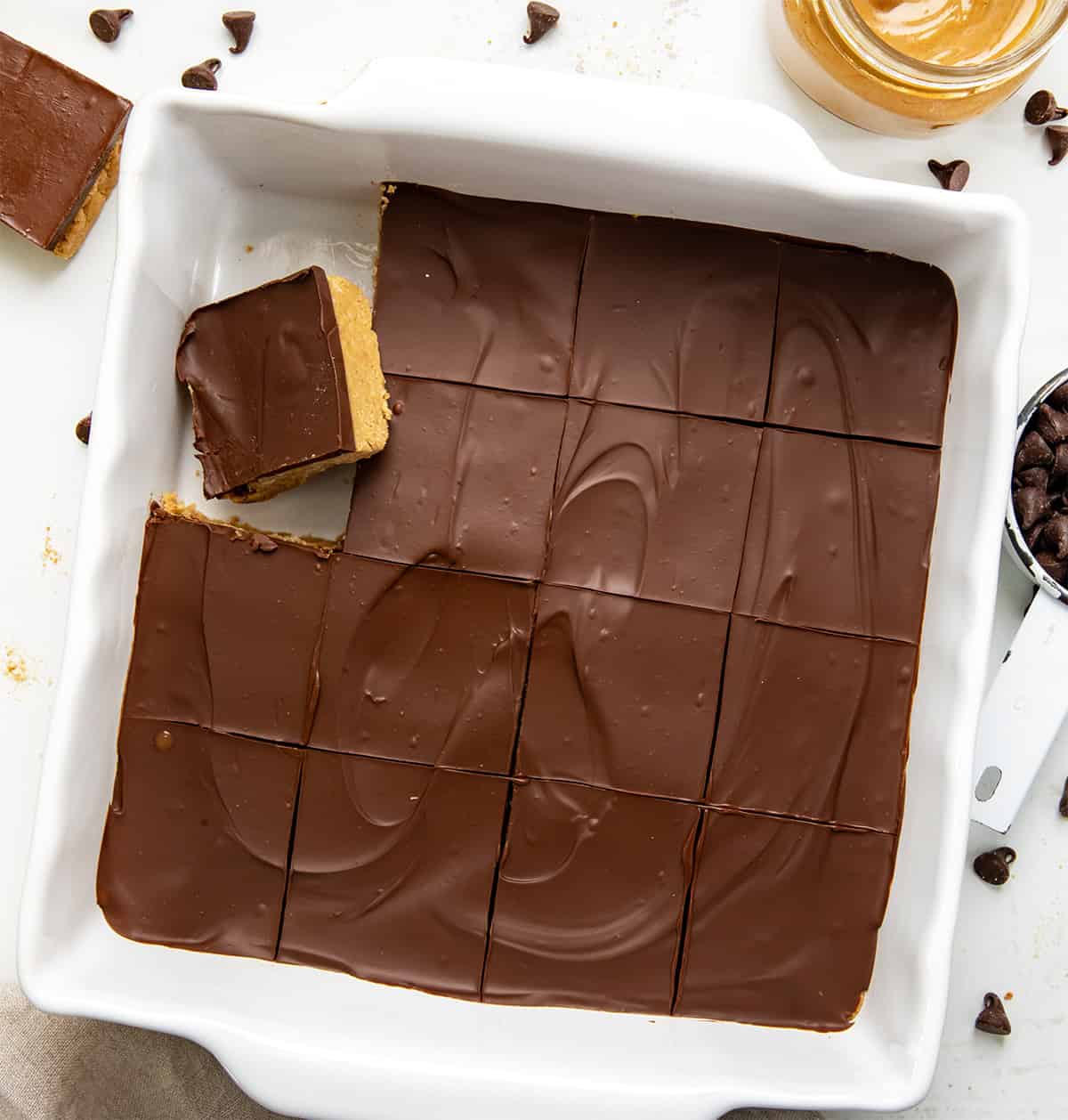 Lunch Lady Peanut Butter Bars are a no-bake dessert with a crunchy graham cracker and peanut butter base topped with a smooth chocolate peanut butter topping. The bars set up in the refrigerator for an easy, delicious treat you can slice and enjoy anytime. Cut up pan of Lunch Lady Peanut Butter Bars with a couple of bars removed.