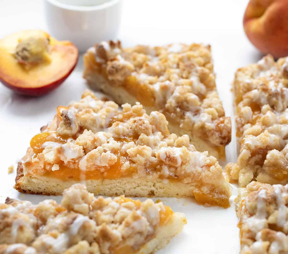 Anytime I see a dessert pizza like Cactus Bread, I want to skip the meal and go straight for the sweet stuff! This Peach Cobbler Pizza starts with my soft, fluffy focaccia bread. On top, you get sweet peaches, a buttery cinnamon crumble, and a drizzle of vanilla glaze. You wonโt want to share! Cut slices of Peach Cobbler Pizza close up.