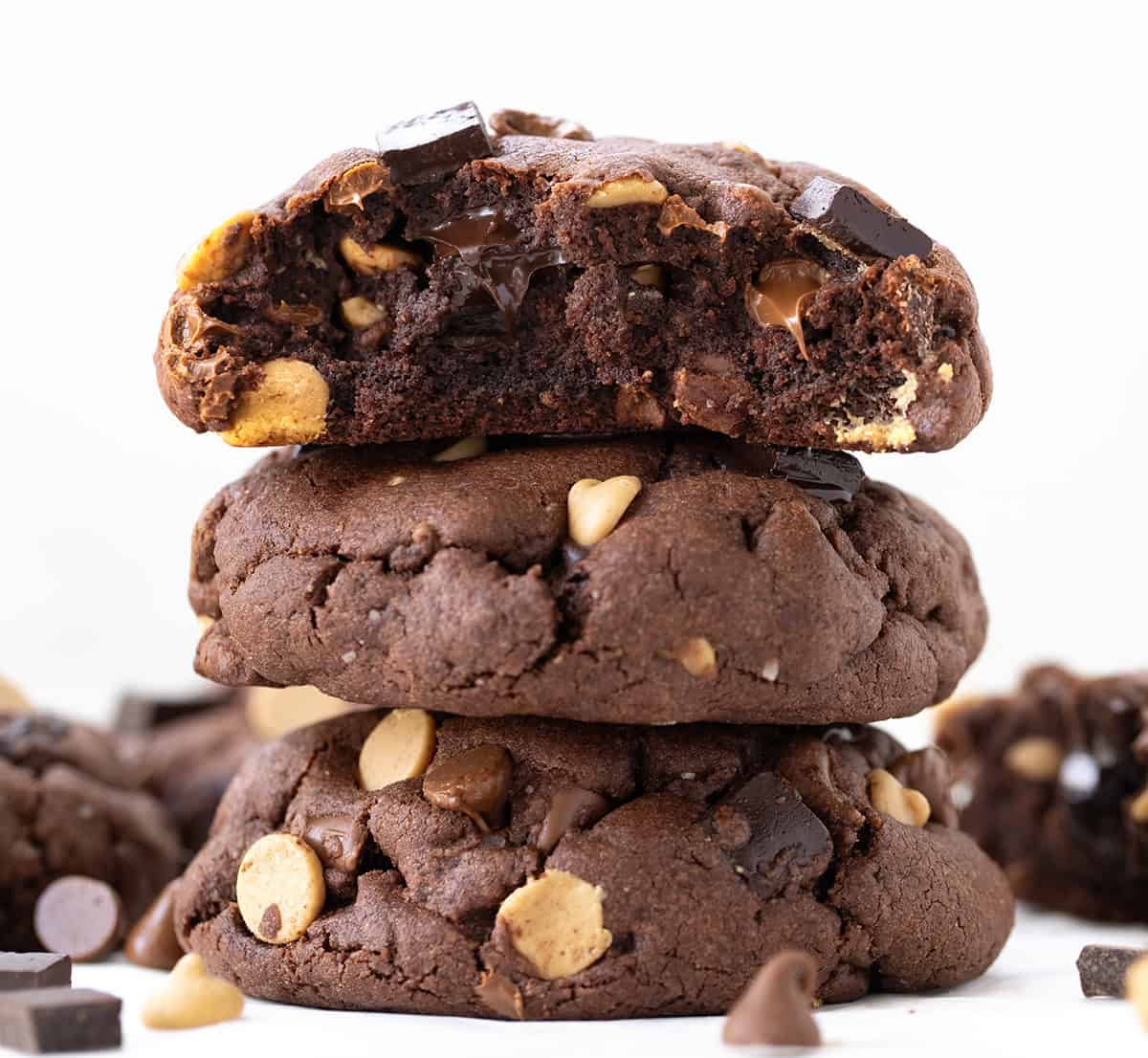 These Peanut Butter Chocolate Chunk Cookies are extra large, extra thick, bakery-style chocolate cookies loaded with semi-sweet chocolate, milk chocolate, and peanut butter chips! Stack of Peanut Butter Chocolate Chunk Cookies with the top cookie broken in half showing the inside.