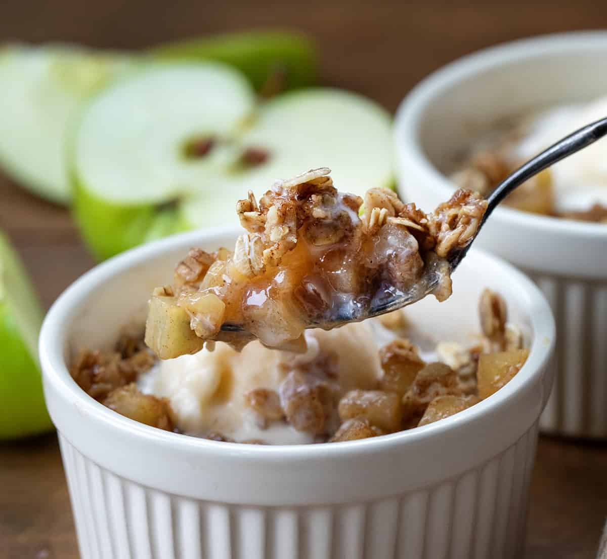 Craving a quick and satisfying dessert? This apple crisp is the perfect single-serve treat. Made with fresh apples and a simple brown sugar oat topping, it comes together in minutes, no oven needed! Spoonful of Apple Crisp being held above the dish.