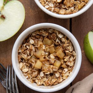 Close up of Single Serve Apple Crisp's on a wooden table with fresh cut apple.