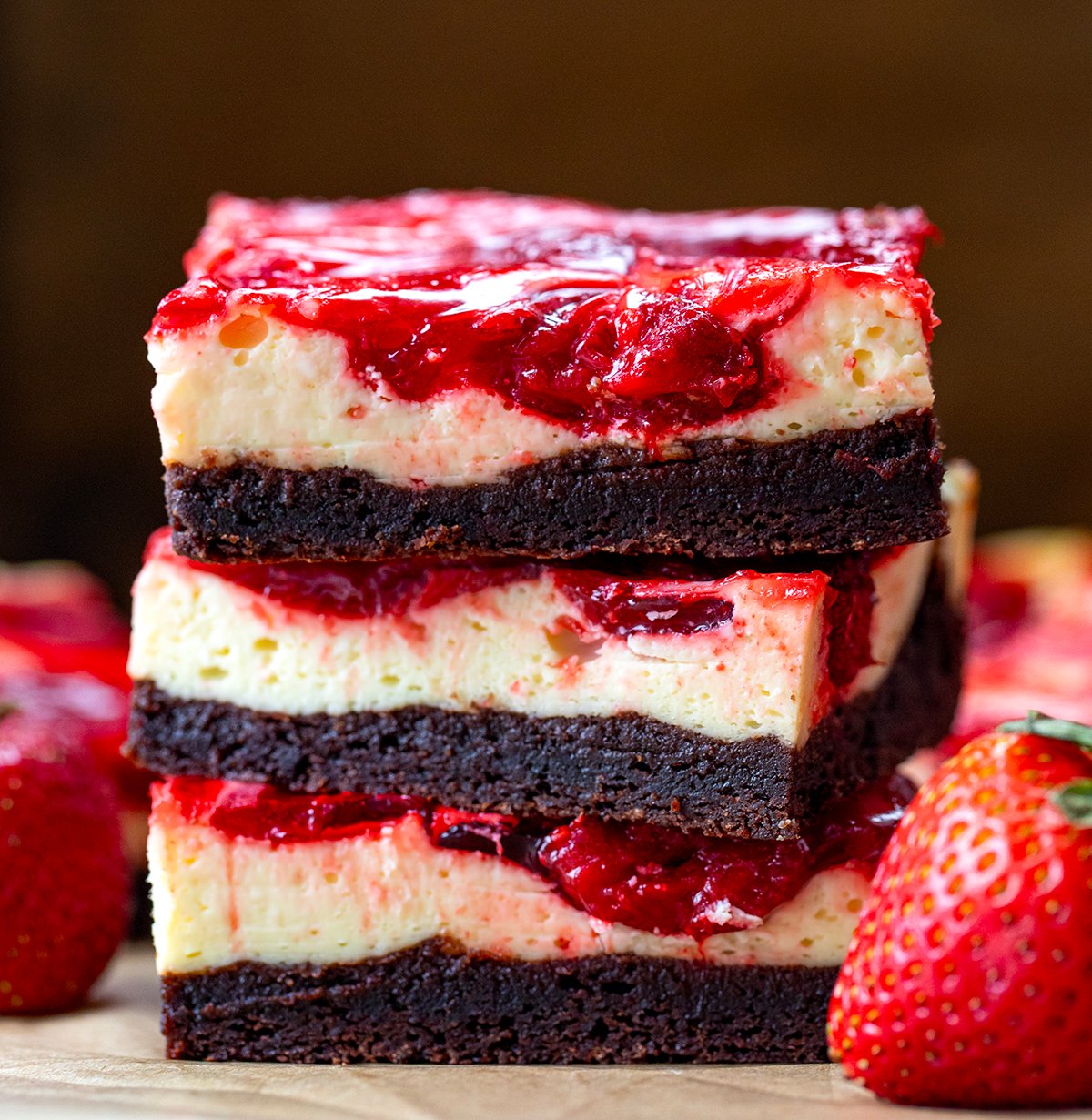 If youโre a fan of rich, fudgy brownies and creamy cheesecake, youโre going to fall hard for these Strawberry Cheesecake Brownies. Itโs like two desserts in one! Stack of Strawberry Cheesecake Brownies on a wooden table close up.