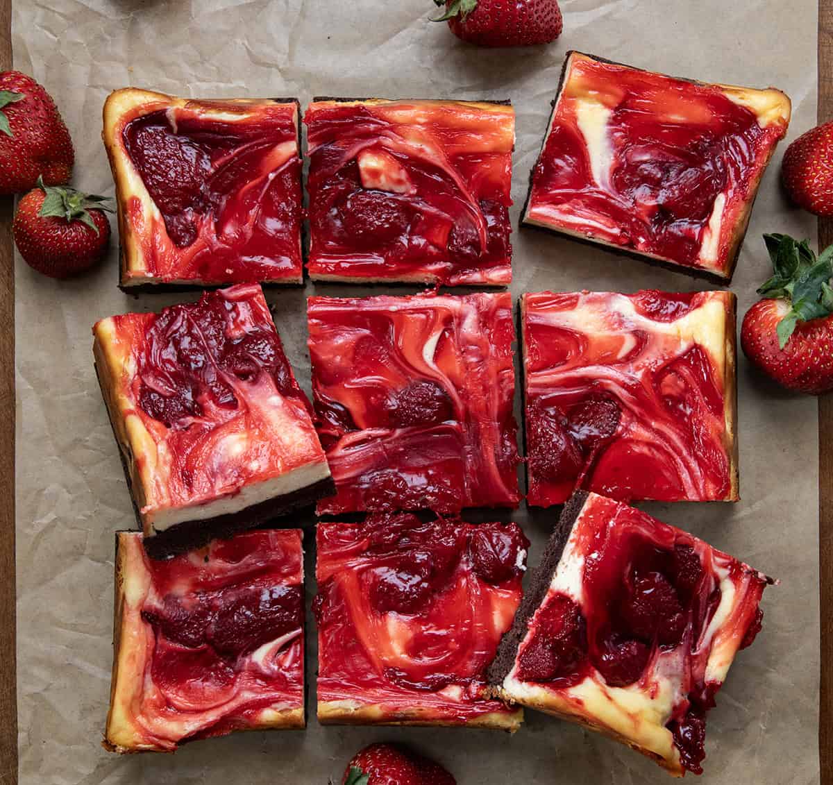 If youโre a fan of rich, fudgy brownies and creamy cheesecake, youโre going to fall hard for these Strawberry Cheesecake Brownies. Itโs like two desserts in one! Strawberry Cheesecake Brownies cut into squares surrounded by fresh strawberries from overhead.