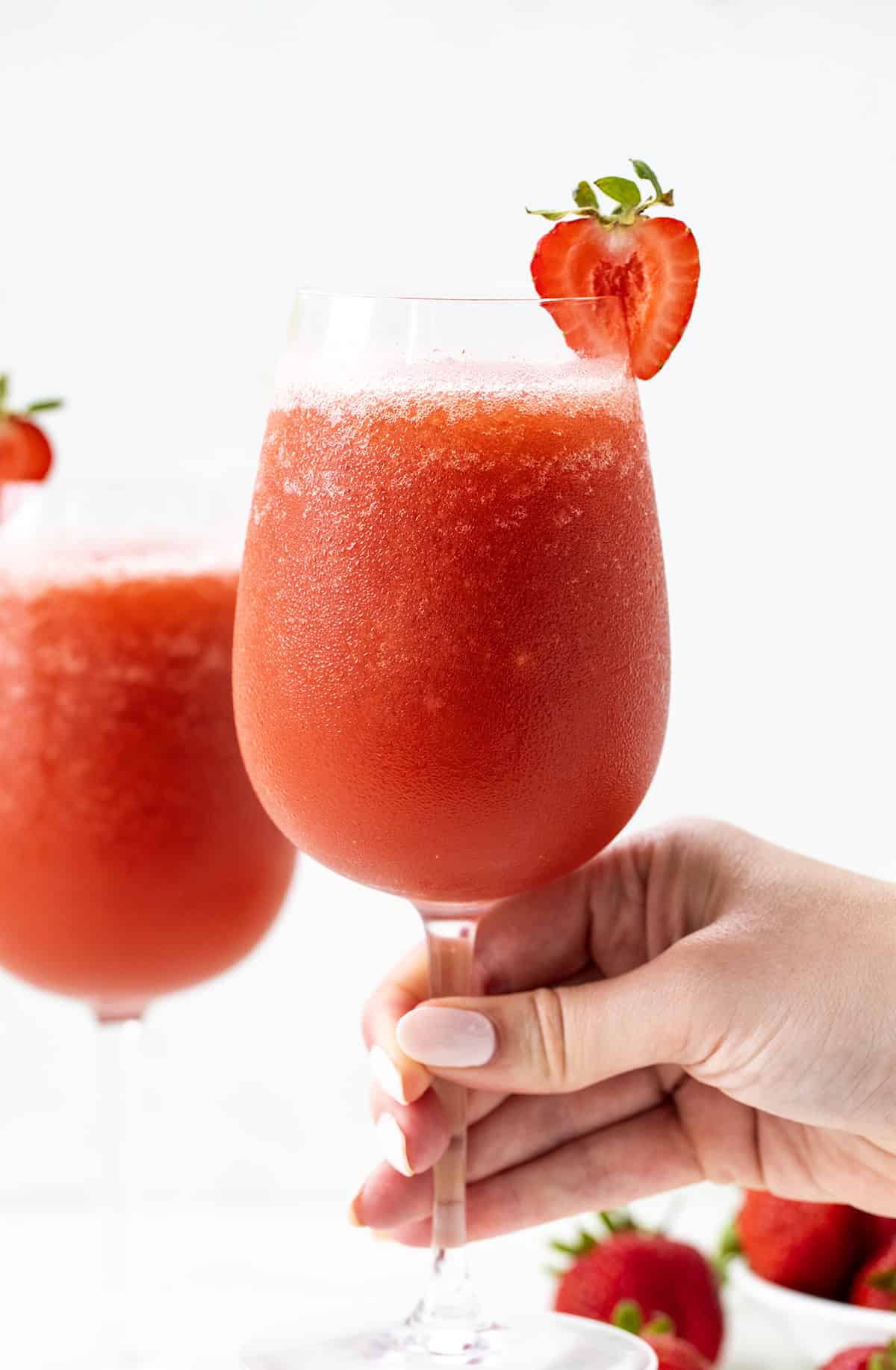Hand holding a glass of Strawberry Frose.