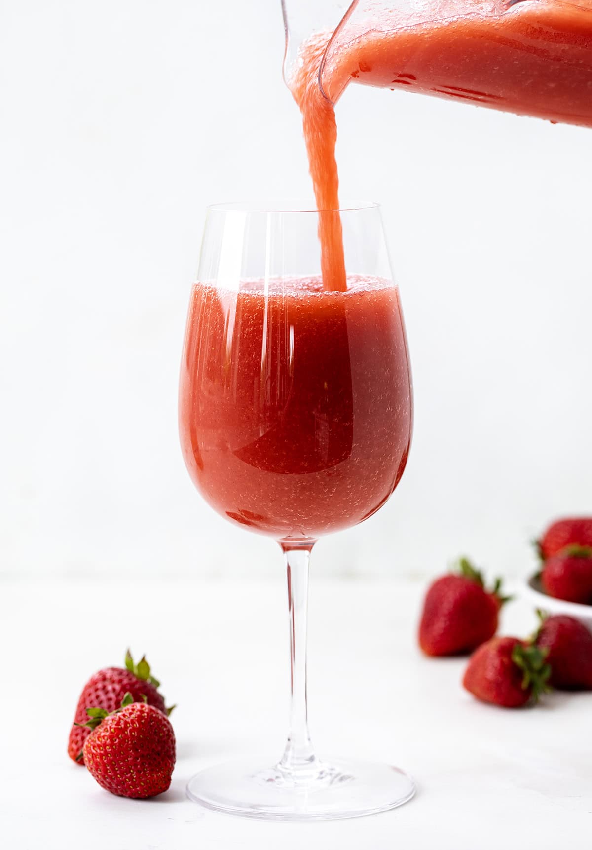 This Strawberry Frosé is cold, fruity, and just what you need (yes, need 😜) on a warm day. Made with frozen strawberries, chilled rosé, and a little sugar, it blends into a smooth, slushy drink that’s perfect for sipping on the patio or sharing with friends! Pouring Strawberry Frose into a glass.