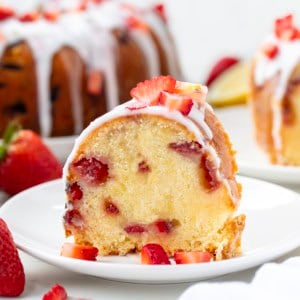 Slice of Strawberry Lemon Pound Cake on a white plate in front of the whole cake.
