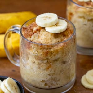 Banana Mug Cakes on a wooden table with bananas.