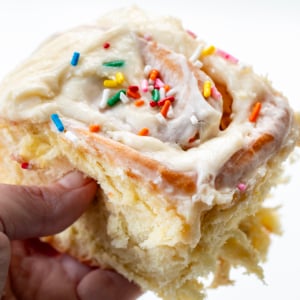 Hand holding a Birthday Cake Cinnamon Roll.