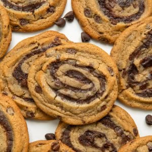 Close up of Brownie Cookie Swirls laying on a white table with chocolate morsels.