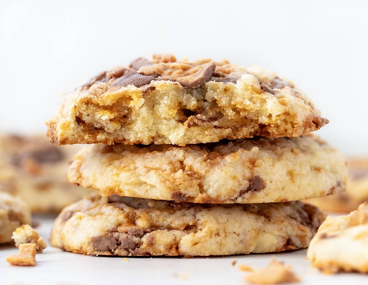 Stack of Butterfinger Cookies with top cookie broken in half showing tender texture inside.